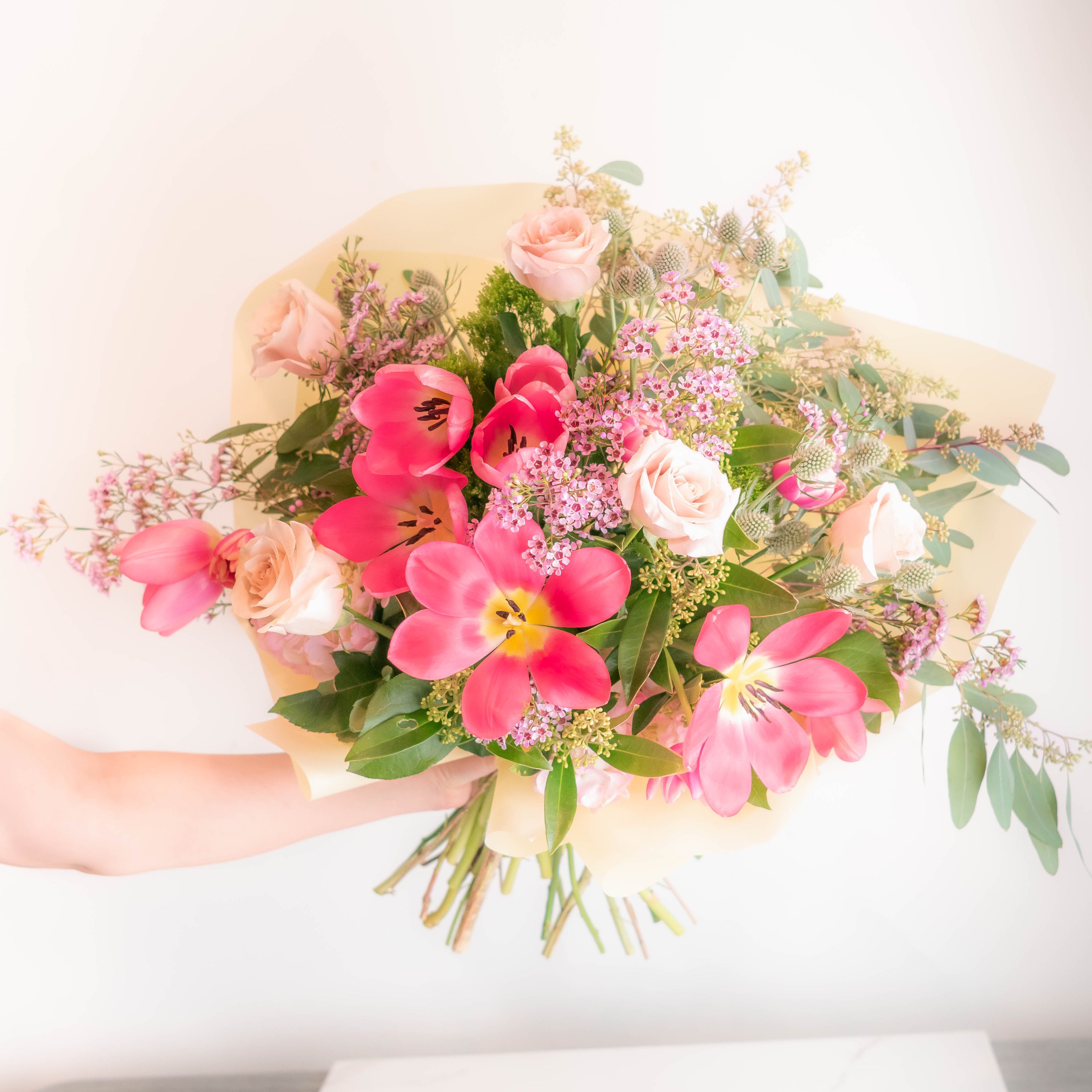 Bouquet of pink and white flowers held by a person on a white background