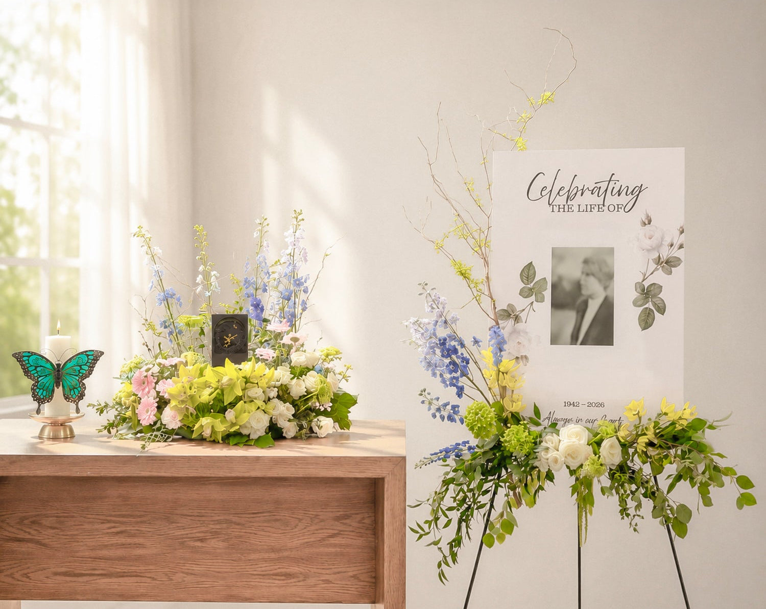 Custom celebration of life flowers featuring blue delphiniums, yellow orchids, white roses and greenery beside a memorial portrait.