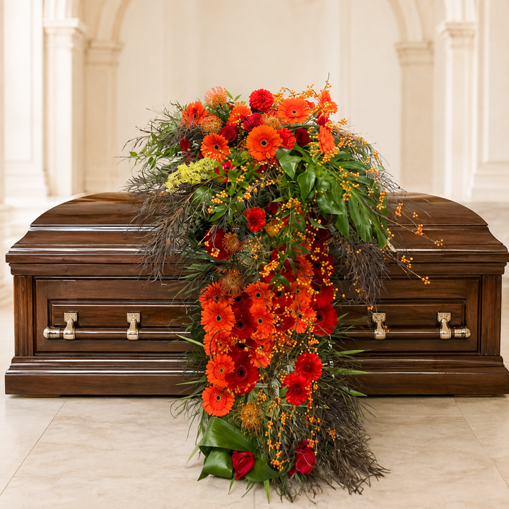 Cascade Casket Spray with orange flowers draping down from the casket all the way to the floor.