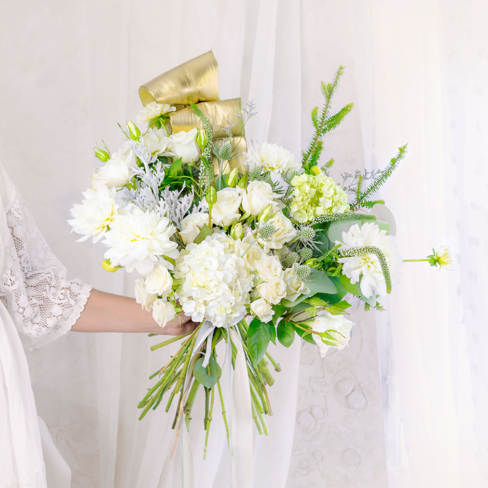 White themed designer's choice bouquet held by a person with white  soft background