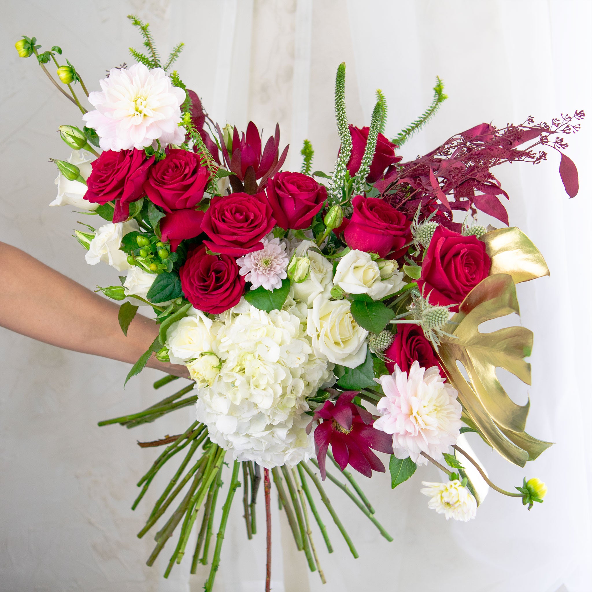 hand holding white and red themed  bouquet
